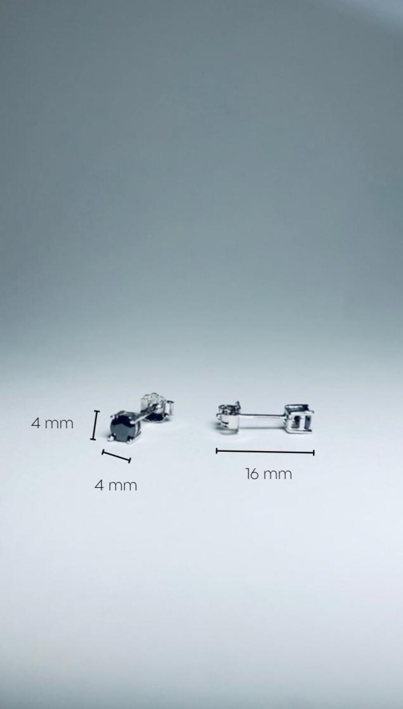 May include: Two pairs of silver stud earrings. One pair features a black gemstone, 4 mm in size. The other pair is 16 mm long. The earrings are displayed on a white surface.
