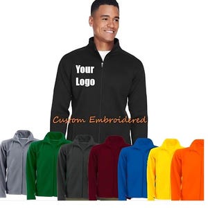May include: A black fleece jacket with a zip fastening and a stand-up collar. The jacket has the text "Your Logo" embroidered on the chest. The jacket is shown in multiple colours: grey, green, black, maroon, blue, yellow, and orange.