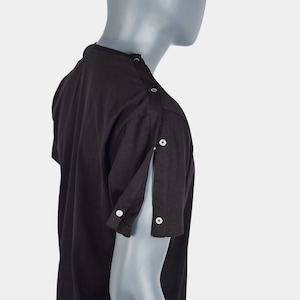 Puede incluir: Camiseta negra de manga corta con cierres a presión en los hombros y las mangas. La camiseta está hecha de una tela suave y cómoda.