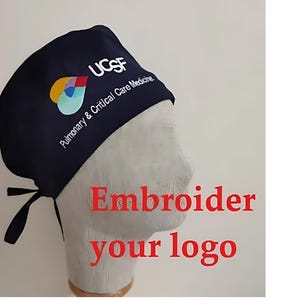 May include: A dark blue surgical scrub hat with a white embroidered logo that says "UCSF Pulmonary & Critical Care Medicine". The logo also includes a colorful design. The text "Embroider your logo" is written in red below the hat.