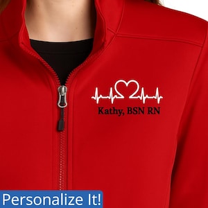 May include: A red zip-up jacket with a white heartbeat graphic and the text "Kathy, BSN RN". The jacket has a black zipper and a black lining.