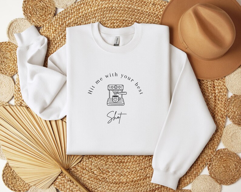May include: White sweatshirt with a black and white illustration of a coffee maker and the text "Hit me with your best shot".