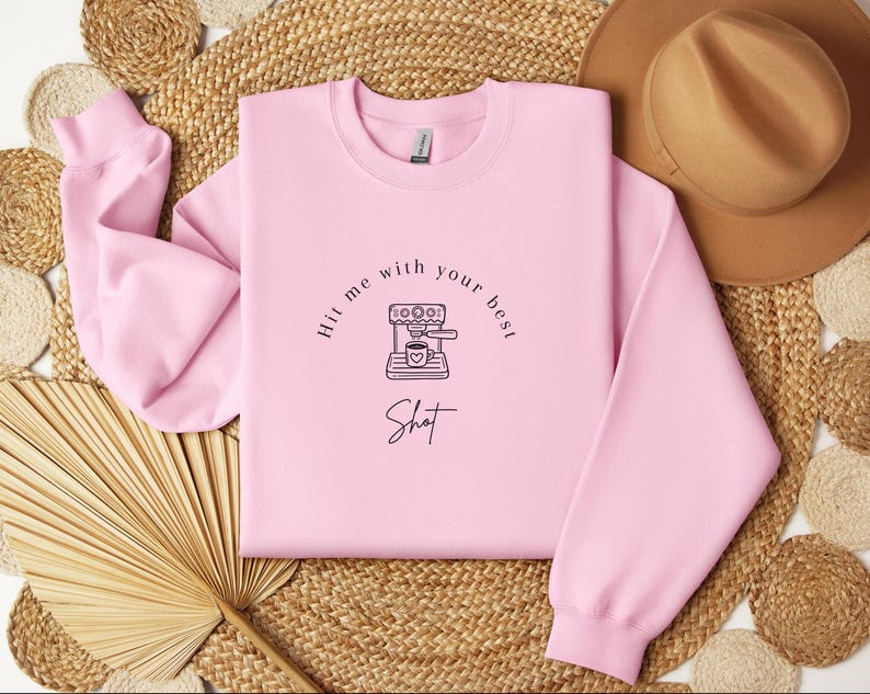 May include: Pink sweatshirt with a black and white illustration of a coffee maker and the text "Hit me with your best shot".