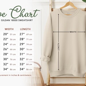 May include: Size chart for a Gildan 18000 sweatshirt, showing measurements in inches and centimeters for sizes S through 5XL. The chart shows width and length measurements for each size.