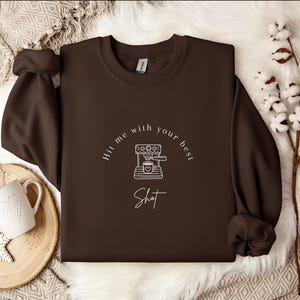 May include: Brown sweatshirt with a white graphic of a coffee maker and the text "Hit me with your best shot".