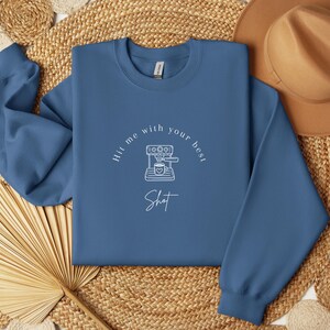 May include: A blue sweatshirt with a white graphic of a coffee maker and the text "Hit me with your best shot".