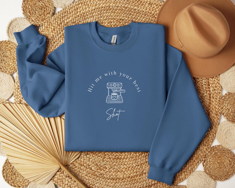May include: A blue sweatshirt with a white graphic of a coffee maker and the text "Hit me with your best shot".
