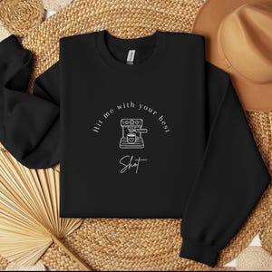 May include: Black sweatshirt with a white graphic of a coffee maker and the text "Hit me with your best shot".