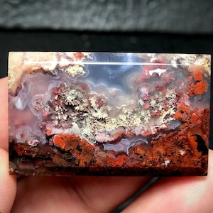 Può includere: Una lastra di agata lucidata con un motivo unico di colori bianco, marrone e rosso. L'agata presenta un aspetto stratificato e a bande con una superficie liscia e lucidata.