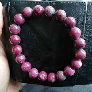 May include: A pink gemstone bracelet with round beads. The bracelet is made of natural stones and has a polished finish.