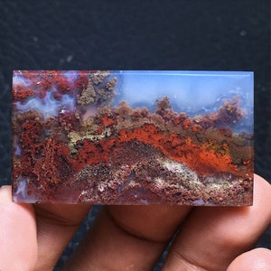 Puede incluir: Una losa de ágata pulida con un patrón de color azul, blanco y rojo. La ágata tiene una apariencia en capas y texturizada con una variedad de colores y patrones.