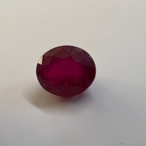 Peut inclure: Une pierre précieuse ovale rouge foncé avec une taille facetée.