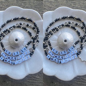 May include: A black and silver beaded necklace with white letter beads spelling out "It Was Rare I Was There" and the numbers 10, 12, and 24.