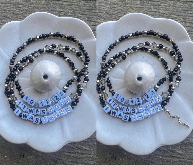 May include: A black and silver beaded necklace with white letter beads spelling out "It Was Rare I Was There" and the numbers 10, 12, and 24.