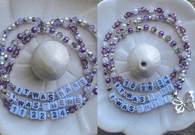 May include: A purple and white beaded necklace with a charm that says "It Was Rare I Was There" with the numbers 10, 26, 24, 11, 22, and 24.