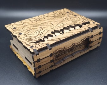 May include: A wooden box with a carved monster design and the text "Monster Book" on the front. The box is made of light brown wood and has a dark brown stain.