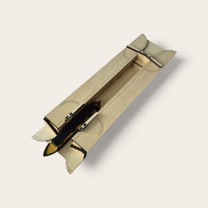 May include: A detailed wooden model of a boat in a canal. The boat is black and gold, and the canal is light brown. The model features cut-out details and curved edges. The boat is centrally positioned within the canal structure.