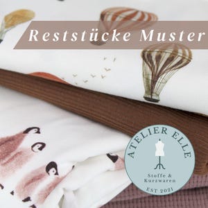 Op de afbeelding: Een stapel stofresten met een heteluchtballonprint en een pinguïnprint. De stofresten zijn van Atelier Ellie, een winkel die stoffen en fournituren verkoopt. De tekst "Reststücke Muster" is zichtbaar bovenaan de afbeelding.