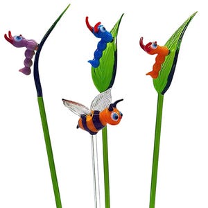 Könnte beinhalten: Drei Glas-Gartenstecker mit bunten Insektenmotiven. Eine lila und blaue Raupe, eine blaue und grüne Raupe und eine Biene mit orange-schwarzen Streifen.