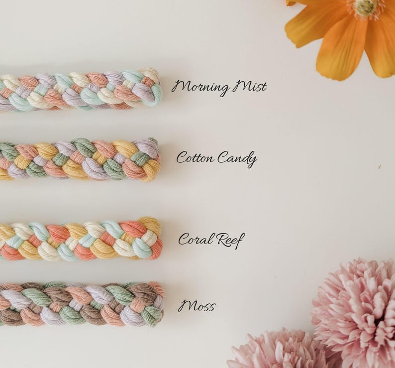 May include: Four braided cords arranged horizontally. The top cord is labeled Morning Mist in pastel tones. The second is Cotton Candy with yellow, pink, and green. The third is Coral Reef in peach and blue. The bottom is Moss in earth tones.