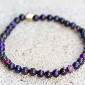 May include: A purple, blue, and black beaded bracelet with a gold clasp.