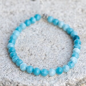 Peut inclure: Un bracelet en pierres pr&eacute;cieuses bleu clair avec des perles rondes. Les perles sont gradu&eacute;es en taille, les plus grosses &eacute;tant en bas du bracelet. Le bracelet est fait avec un fermoir argent&eacute;.