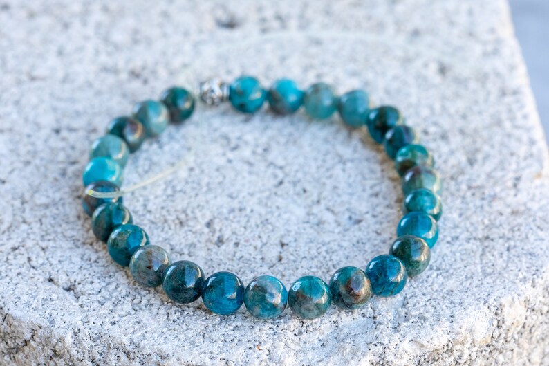 Pu&ograve; includere: Un braccialetto di pietre blu con accenti argentati. Il braccialetto &egrave; fatto di perline rotonde ed &egrave; infilato su un cordoncino elastico trasparente.