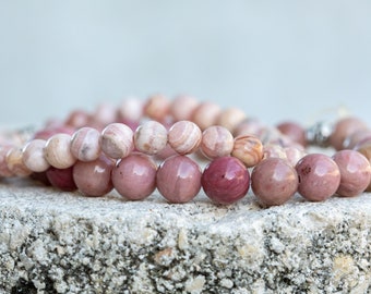 May include: Two pink and white gemstone bracelets with round beads. The bracelets are made of natural stones and are stacked on top of each other.