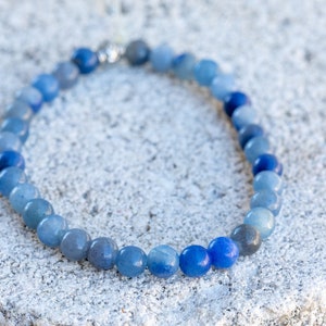 May include: A blue gemstone bracelet with beads that gradually transition from light to dark blue.