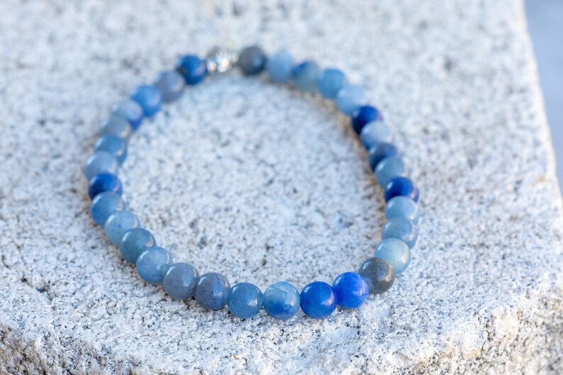 May include: A blue gemstone bracelet with beads that gradually transition from light to dark blue.
