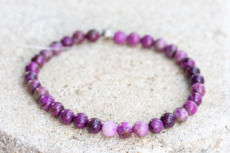 May include: A purple and white gemstone bracelet with a silver clasp.