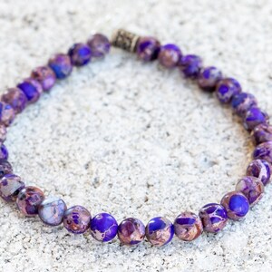 May include: A purple and brown beaded bracelet with a silver clasp.