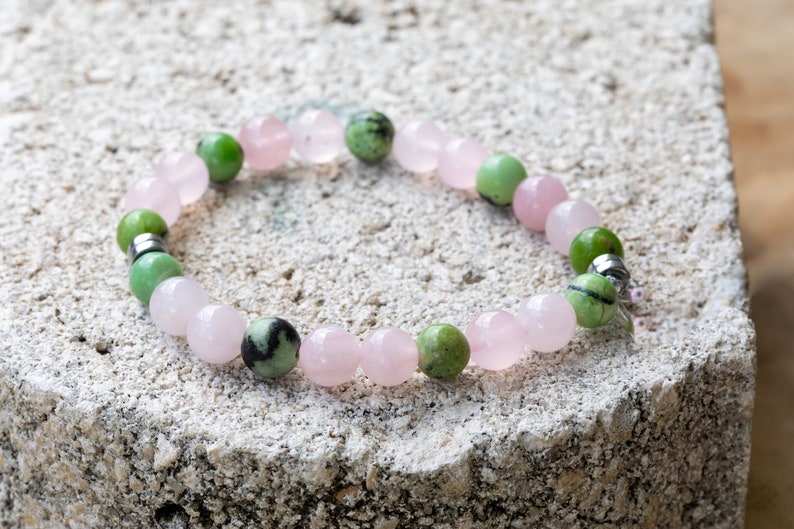 K&ouml;nnte beinhalten: Ein Armband aus rosafarbenen und gr&uuml;nen Edelsteinperlen. Das Armband hat einen silbernen Verschluss.