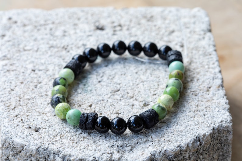 K&ouml;nnte beinhalten: Ein gr&uuml;nes und schwarzes Perlenarmband mit schwarzen Lavasteinen und gr&uuml;nen Serpentinperlen.