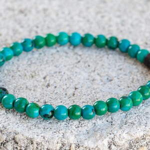 May include: A turquoise green beaded bracelet with a dark brown accent bead.