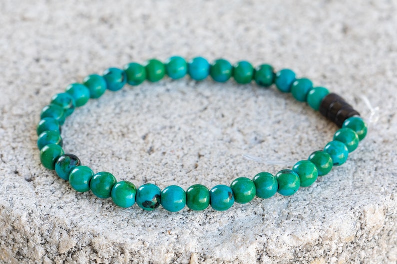 May include: A turquoise green beaded bracelet with a dark brown accent bead.