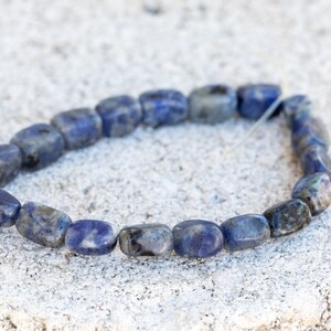 May include: A bracelet made of blue and white lapis lazuli beads. The beads are rectangular and have a smooth, polished finish.