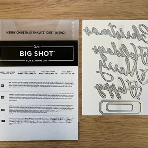 May include: A set of silver metal die cuts for a craft project. The die cuts are in the shape of the words "Christmas", "Holidays", "Merry", and "Happy". There is also a rectangular die cut with a decorative border.