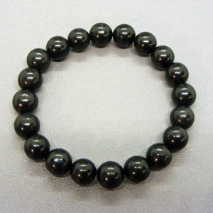 Könnte beinhalten: Ein schwarzes Armband aus runden, glatten, polierten Steinen.