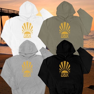 May include: Four hooded sweatshirts in different colors: white, green, gray, and black. Each sweatshirt features a yellow sunburst graphic with the text "OBX" in the center.