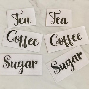 May include: Six white labels with black cursive text. The labels read "Tea", "Coffee", "Sugar", "Tea", "Coffee", and "Sugar".