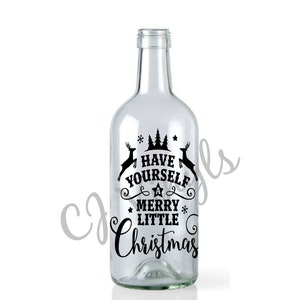 May include: A clear glass wine bottle with a black vinyl sticker that reads "Have Yourself a Merry Little Christmas". The sticker features a stylised Christmas tree, a star, and a reindeer.