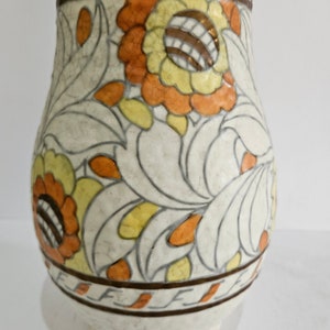 May include: A white ceramic vase with a floral design in shades of orange, yellow, and brown. The vase has a rounded body and a narrow neck.