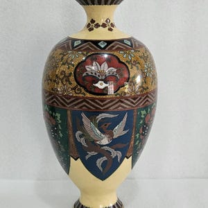 Può includere: Un grande vaso in ceramica color crema con un designo floreale e di uccelli in oro e multicolore. Il vaso ha un corpo rotondo e un collo svasato.