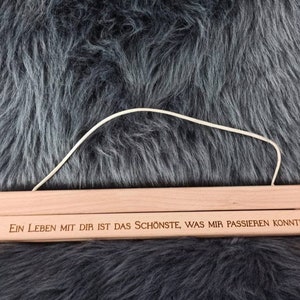 Puede incluir: Un colgador de p&oacute;ster de madera con una cuerda blanca atada. El colgador tiene el texto "Ein Leben mit dir ist das Sch&ouml;nste, was mir passieren konnte" grabado.