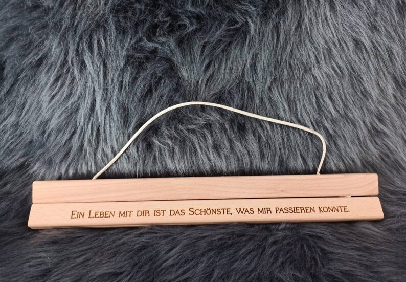 Puede incluir: Un colgador de p&oacute;ster de madera con una cuerda blanca atada. El colgador tiene el texto "Ein Leben mit dir ist das Sch&ouml;nste, was mir passieren konnte" grabado.