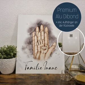 Puede incluir: Una ilustraci&oacute;n de acuarela de cuatro manos, que representan a una familia, con el texto "Familie Inanc" debajo. La imagen est&aacute; impresa en un panel de Dibond de aluminio blanco con un gancho para colgar en la parte posterior.
