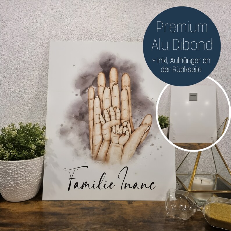 Puede incluir: Una ilustraci&oacute;n de acuarela de cuatro manos, que representan a una familia, con el texto "Familie Inanc" debajo. La imagen est&aacute; impresa en un panel de Dibond de aluminio blanco con un gancho para colgar en la parte posterior.