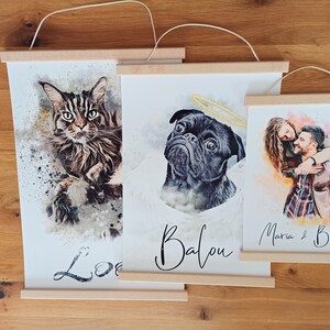 Puede incluir: Tres pinturas de acuarela enmarcadas sobre una superficie de madera. La primera pintura presenta un gato con el nombre "Lola" escrito debajo. La segunda pintura presenta un carlino con el nombre "Balou" escrito debajo. La tercera pintura presenta una pareja con los nombres "Maria & Ben" escritos debajo.