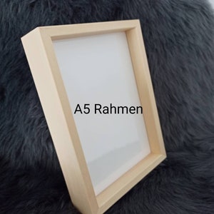 Puede incluir: Un marco de fotos de madera clara con un paspart&uacute; blanco y el texto "A5 Rahmen" impreso en el paspart&uacute;.